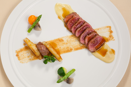 Tagliata di agnello in crosta di funghi porcini con piccolo hamburger su millefoglie di patate e crema pastinache